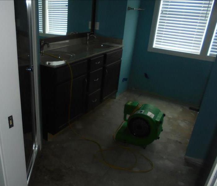 Blue bathroom with SERVPRO equipment on the floor. 